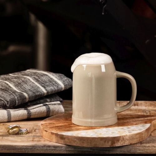 Stenen bierpul van aardewerk 50 cl. gevuld met bier, geplaatst in sfeervolle horeca-omgeving.