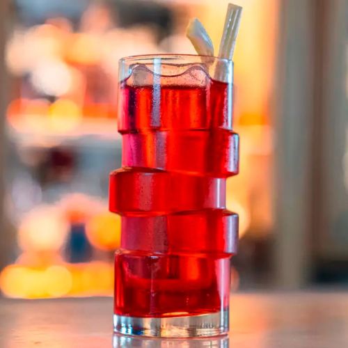 The Glitch longdrink glas 40 cl. gevuld met drank en voorzien van logo in een sfeervolle setting.