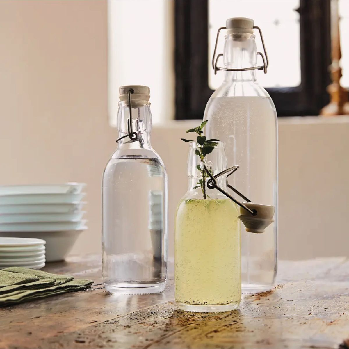 Emilia 1-litre bottle with bracket closure and filling, with printed logo in kitchen setting.